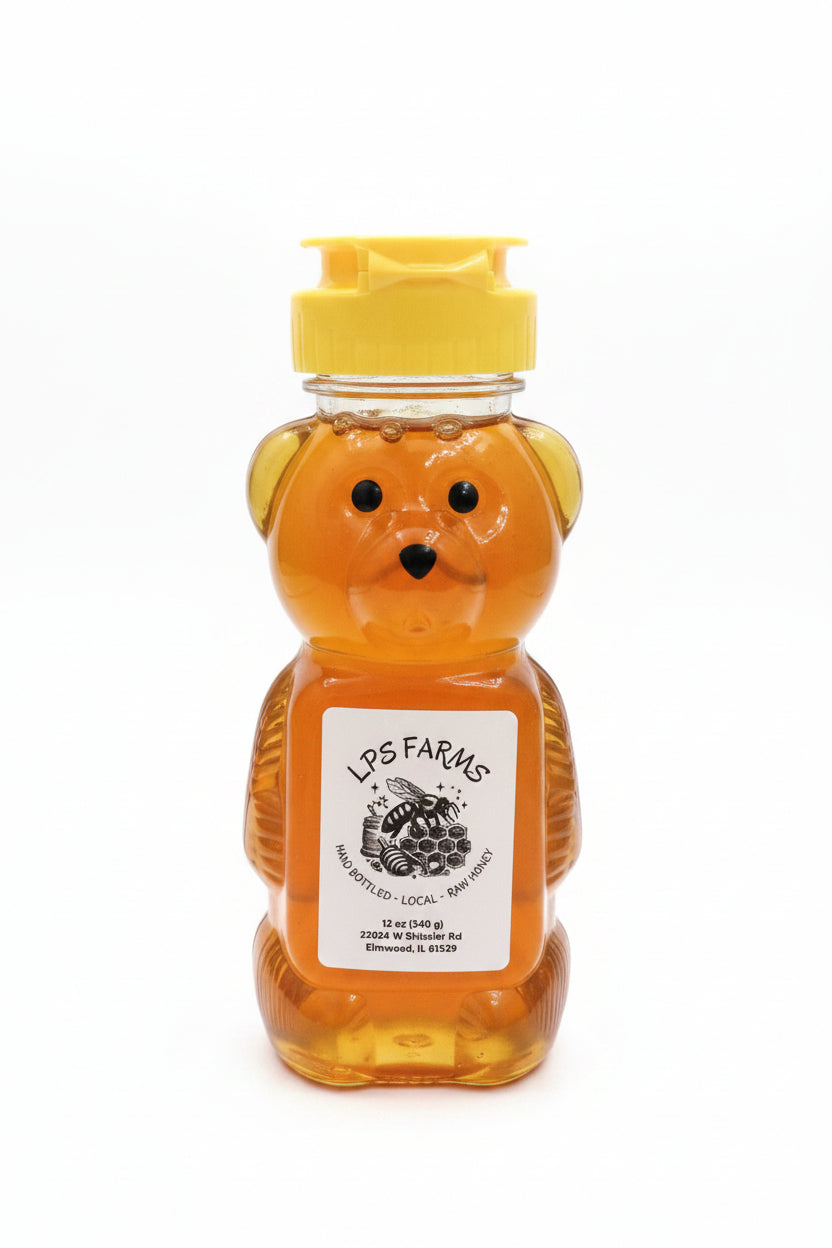 Honey bear bottle with yellow lid on a wooden table, featuring LPS Farms label.
