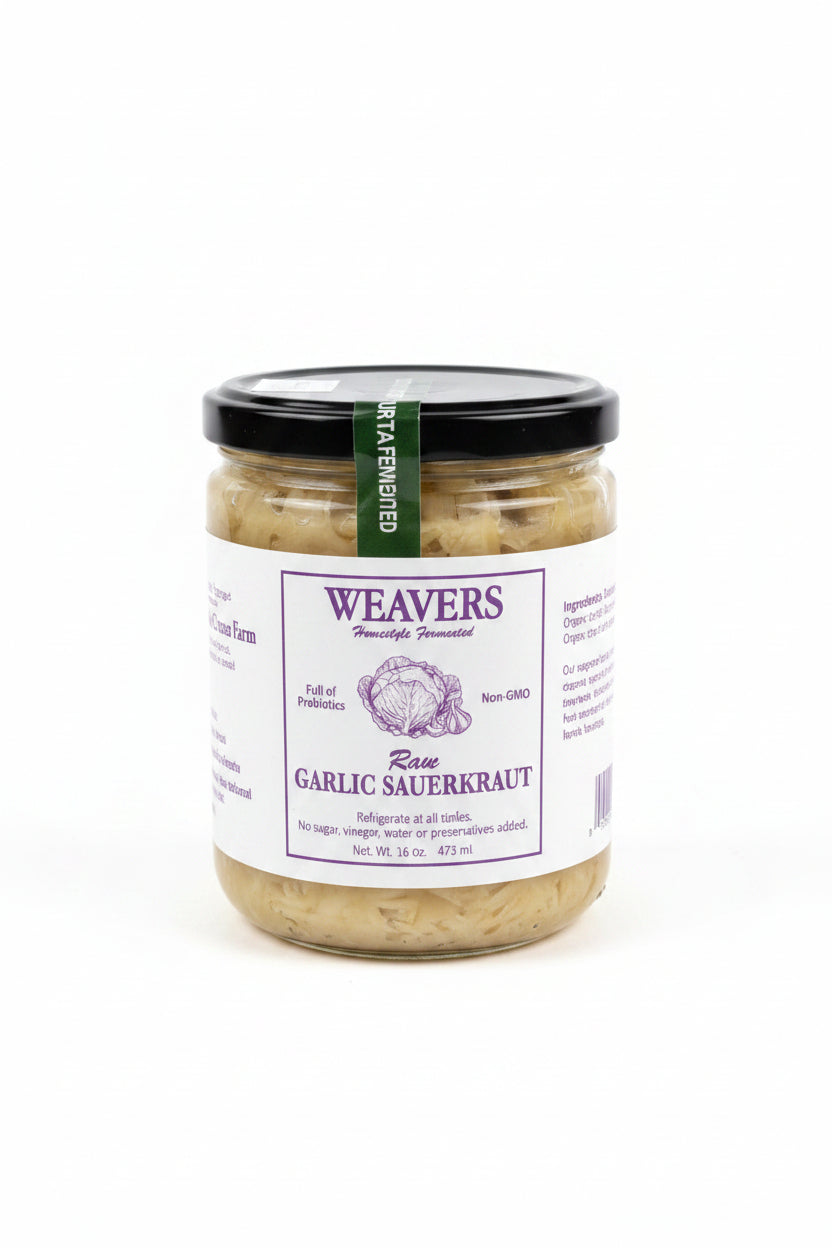 A jar of Weavers Rose Garlic Sauerkraut on a clean white background. The glass jar shows the pale beige sauerkraut inside, topped with a black lid and a white label featuring purple text and a purple cabbage illustration.
