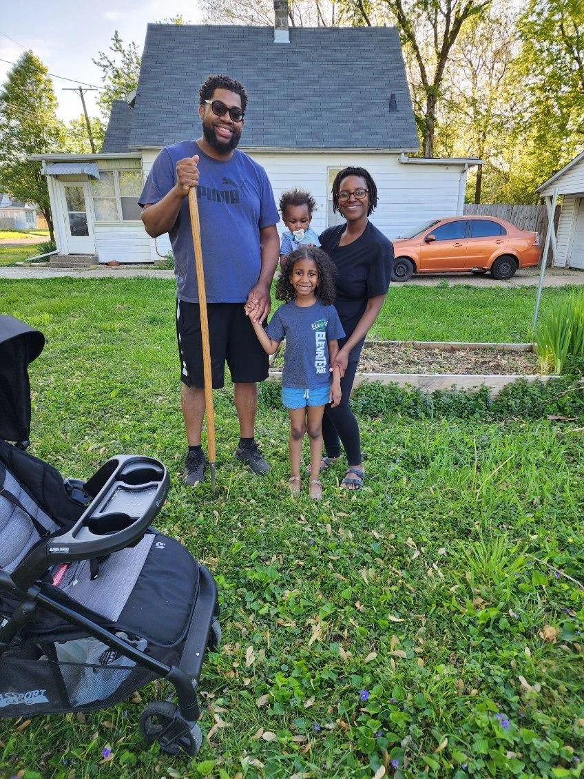 Family of four with a stroller in a residential yard.