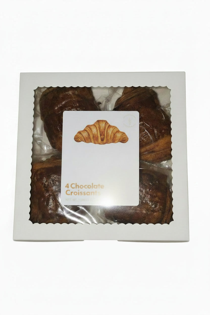 A white square box of chocolate croissants with a clear window and a central label showing an image of a croissant and the text '4 Chocolate Croissants'.