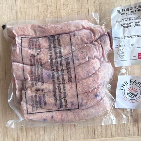 Packaged sausage meat products with visible branding on a wooden surface