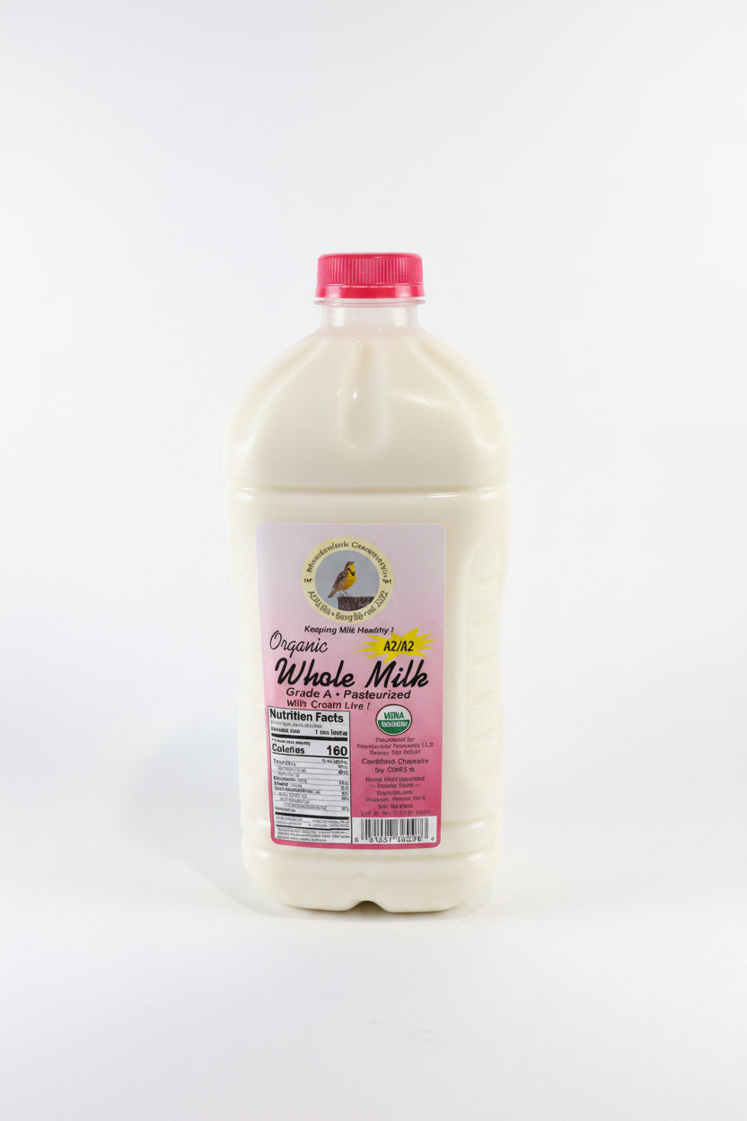 Bottle of organic whole milk with a pink label on a white surface.